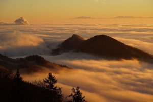 Amanecer dorado sobre montañas cubiertas por una espesa niebla, simbolizando la paz y el viaje eterno